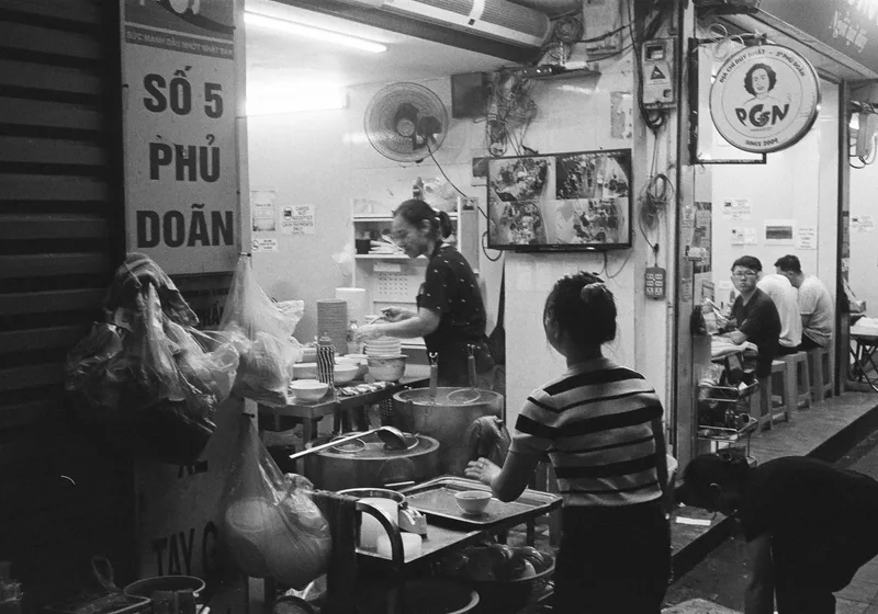 Hanoi street restaurant shot on Ilford HP5 Plus 400 with a Rollei 35, by Nicolai Gjellestad